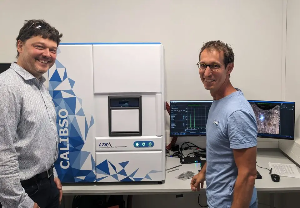 Employees with the CALIBSO analysis system in the laboratory, supported by modern software on two monitors.